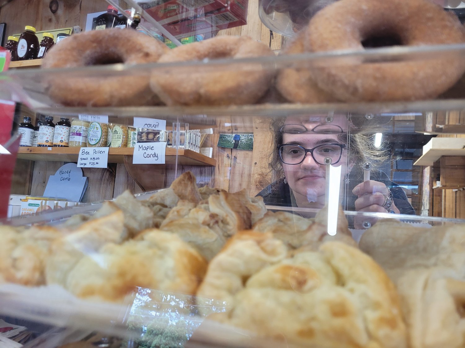 DONUTS & DUMPLINGS: Appleland employee Sara Groves looks through the back of a display case at the orchard store, which sells fresh apple cider donuts and apple dumplings, and will be bringing their tasty treats to this year’s Johnston Apple Festival.
